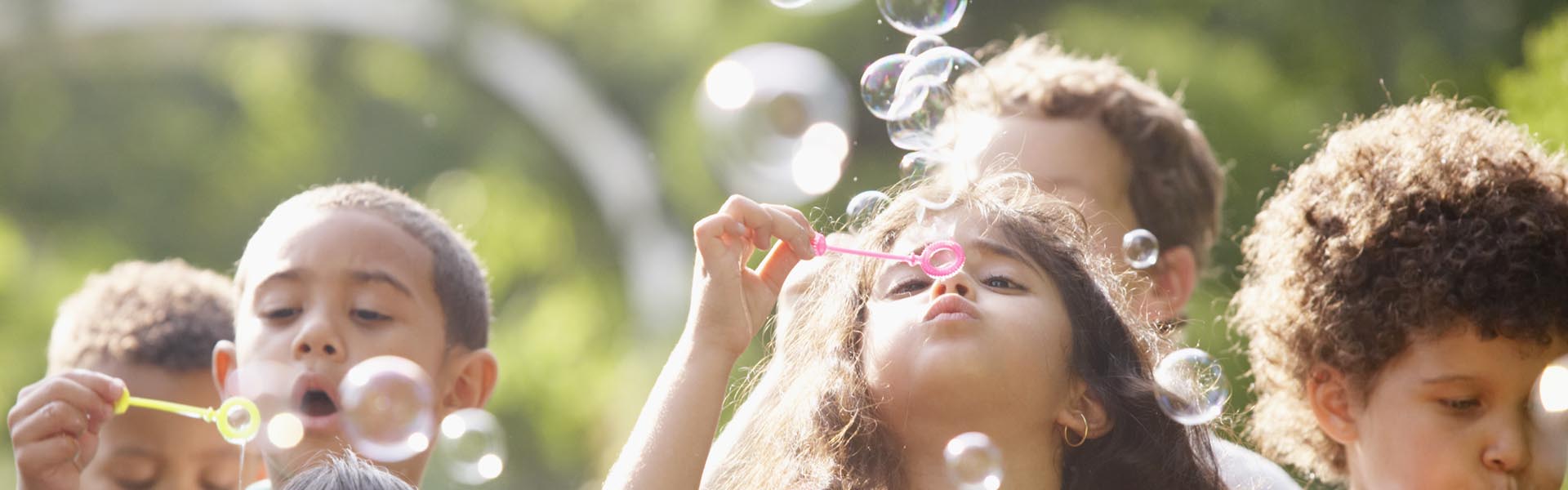 on a sunny day a few children blow soap bubbles